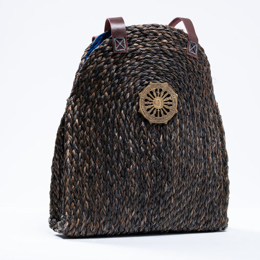 Front view of the Dokra Sabai Joda Bag in deep charcoal brown with prominent Dokra brass emblem