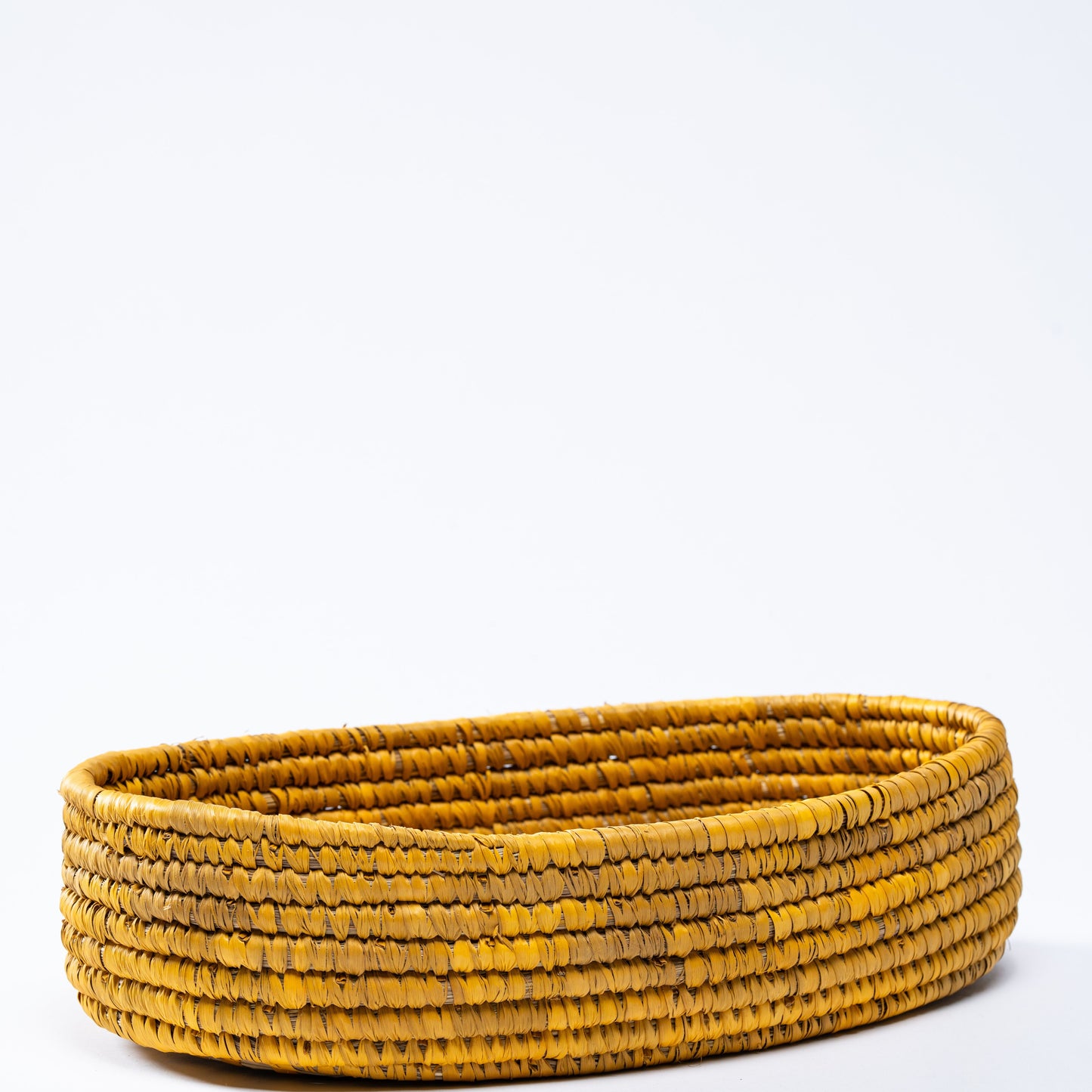 Full side view of the yellow oval basket on a white background, emphasizing its oval shape.