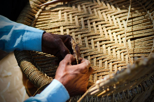 Artisan's hands weaving a natural fibre basket