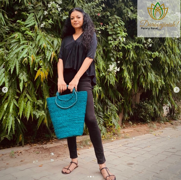 Woman carrying a teal sabai grass basket bag outdoors