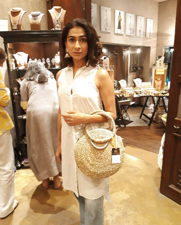 Woman with a natural sabai grass basket bag in a craft store