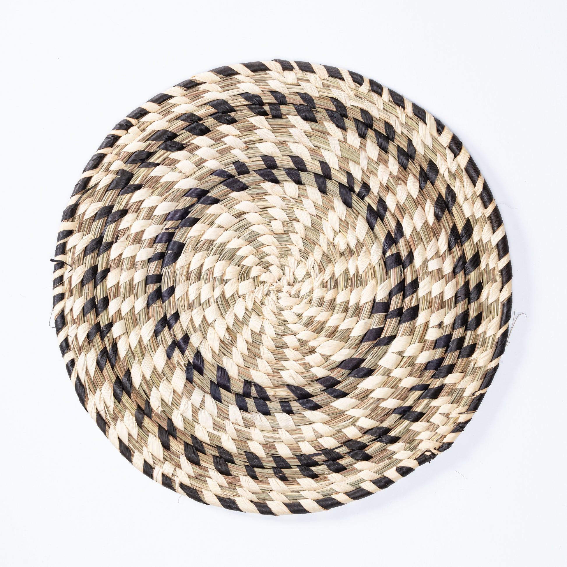 Black and white handwoven Sabai grass plate mat top view