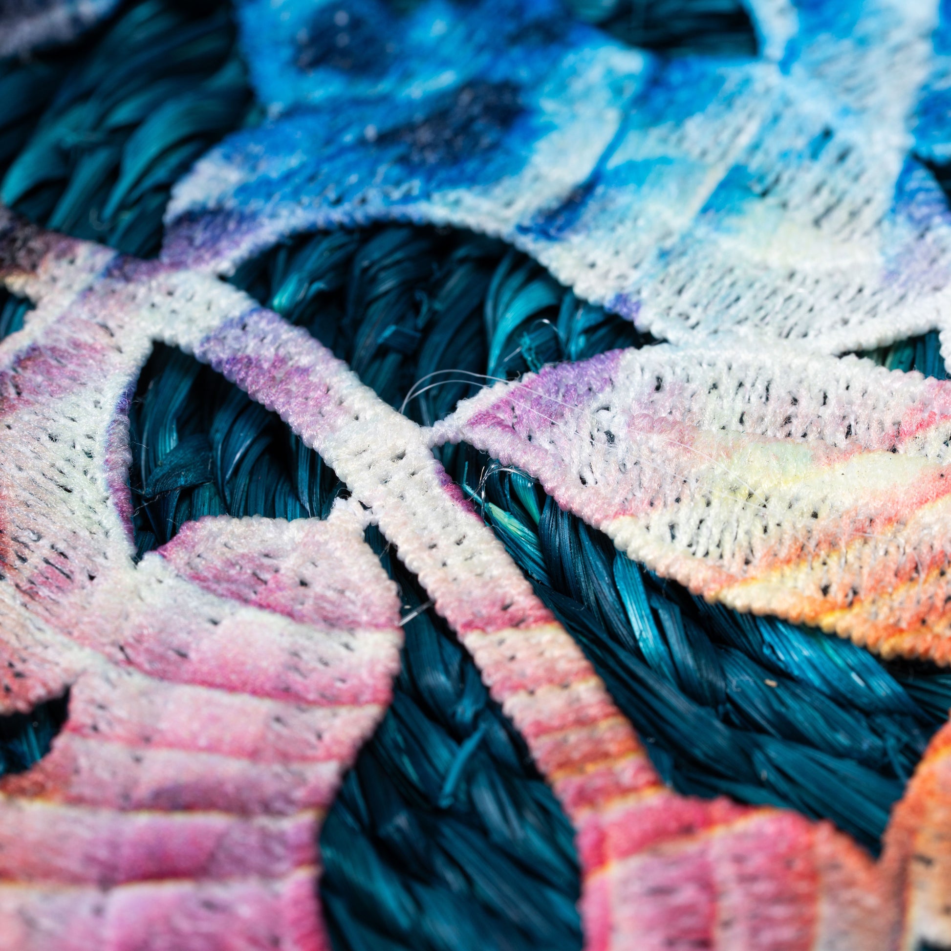 Pink embroidered border corner on indigo sabai mat

