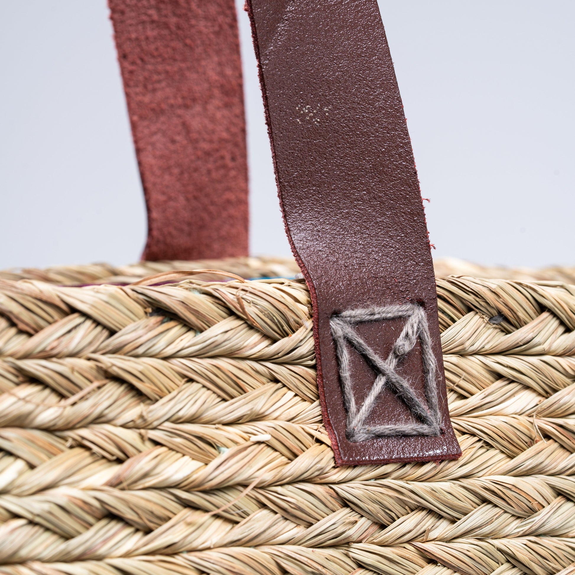 Back view of Indrani Sabai artisan basket bag highlighting natural weave and leather straps