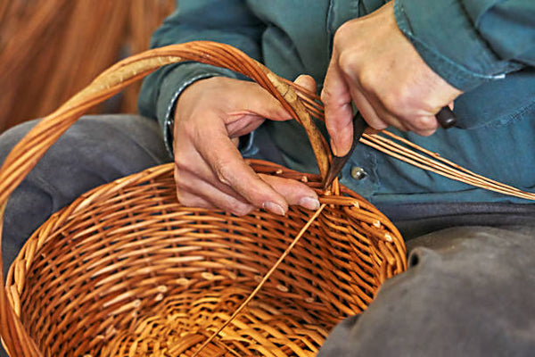 Craftsman weaving a round basket by hand