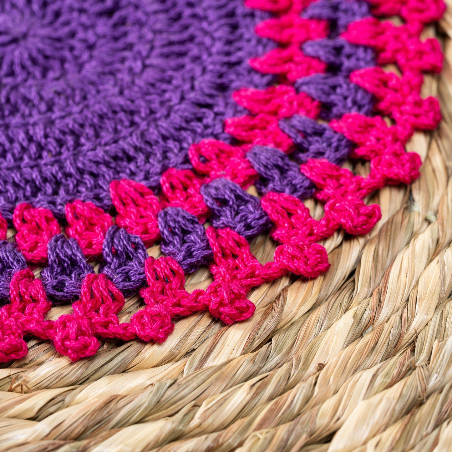 Close-up of pink and purple crochet detailing on mat – macro shot

