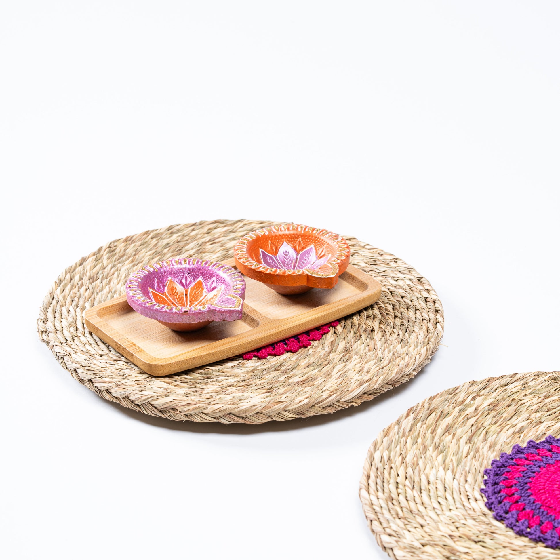 Decorative diyas placed on sabai mat with wooden tray – styling shot

