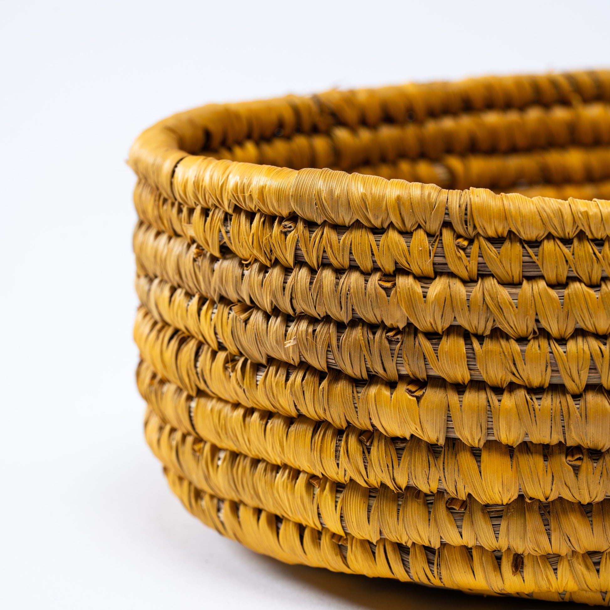 Close-up view of the yellow oval basket highlighting its handwoven texture and natural fibers.

