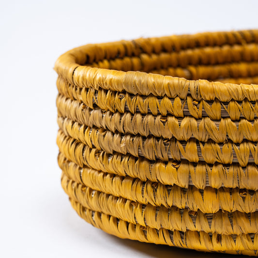 Close-up view of the yellow oval basket highlighting its handwoven texture and natural fibers.

